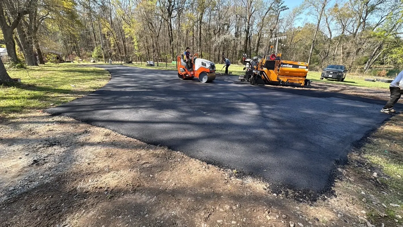 Asphalt Appeal paver mid-run on a long driveway through a wooded property